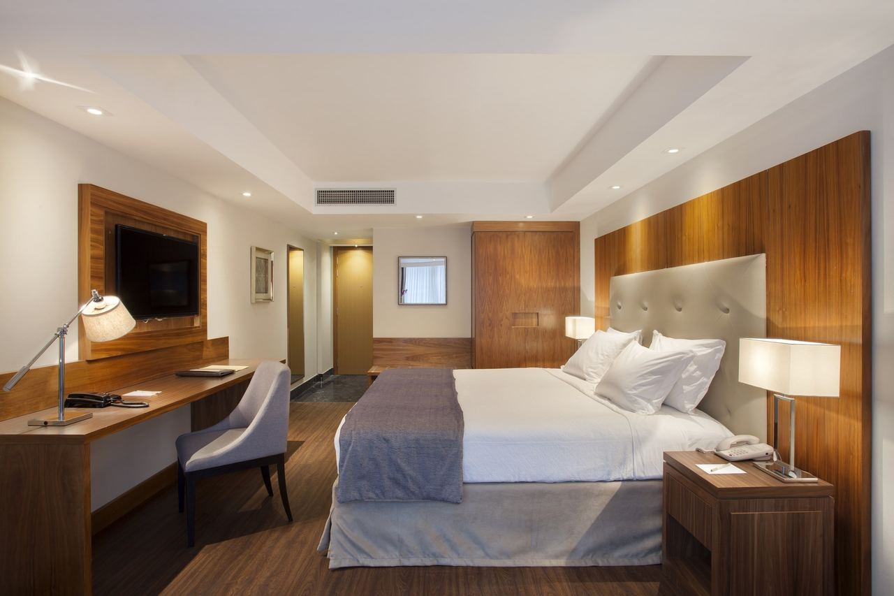 A bedroom at the Windsor Marapendi, with a wood-panelled wall and upholstered headboard
